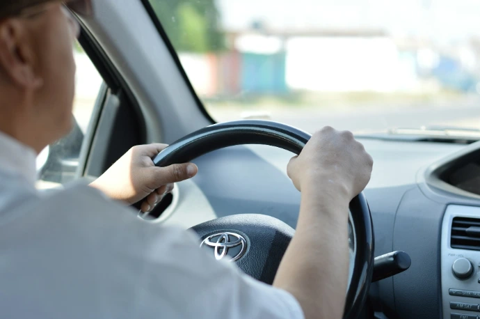 person in white long sleeve shirt driving car
